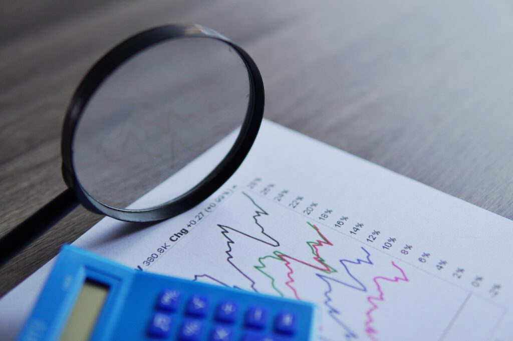 Closeup image of calculator, magnifying glass and line graph.
